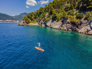 Young women Having Fun Stand Up Paddling in blue water sea in Montenegro. SUP. girl Training on...