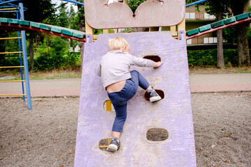 Back view cute adorable caucasian blond little toddler boy kid having fun climbing stairs at modern...