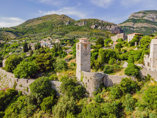 Fototapeta premium Old city. Sunny view of ruins of citadel in Stari Bar town near Bar city, Montenegro. Drone view Portrait of a disgruntled girl sitting at a cafe table