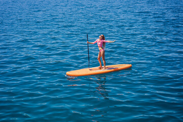 Young women Having Fun Stand Up Paddling in blue water sea in Montenegro. SUP. girl Training on...