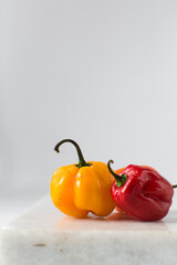 Yellow and red scotch bonnet pepper with stem on a marble board, fresh pepper, yellow pepper,...