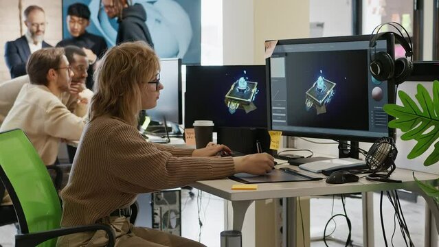 Caucasian female artist designer in glasses draws 3D model for a computer game in the office of a project development studio. 