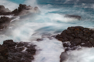 Waves crashing over lava rocks on shoreline of Espanola Island, Galapagos Islands, Ecuador.