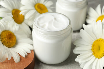 Obraz na płótnie Canvas Jars of face cream and beautiful chamomiles on grey table