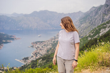 Naklejka premium Woman tourist enjoys the view of Kotor. Montenegro. Bay of Kotor, Gulf of Kotor, Boka Kotorska and walled old city. Travel to Montenegro concept. Fortifications of Kotor is on UNESCO World Heritage