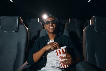 african american man in 3d glasses eating popcorn and watching film in cinema