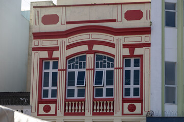 Beautiful architecture of an old building. The pediment of an ancient building with windows and a balcony. White building with red architectural forms and windows.