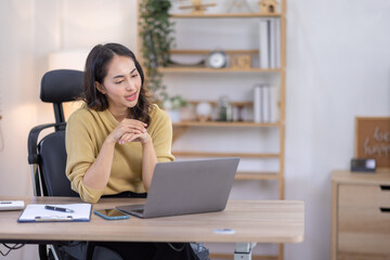 Obraz premium Image of young indian pleased happy cheerful cute beautiful business Asian woman sit indoors in home office using laptop computer talking in a video conference on line 