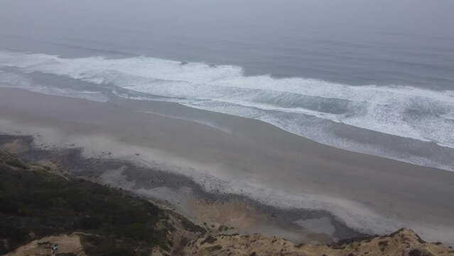 Aerial drone view of yellow sandstone cliffs gliding towards pacific coastline  during a foggy morning, Torrey Pines State Natural Reserve, San Diego, California
