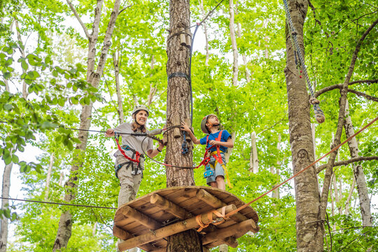 Mother and son climbing in extreme road trolley zipline in forest on carabiner safety link on tree to tree top rope adventure park. Family weekend children kids activities concept Portrait of a