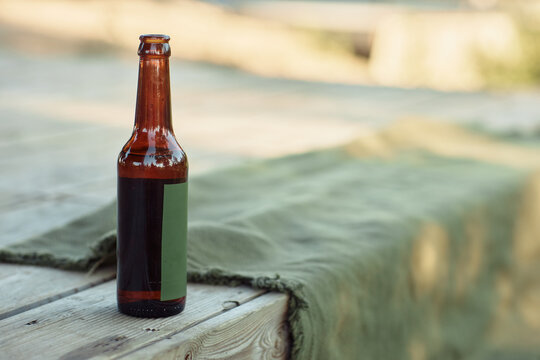Close up background image of single beer bottle on wooden pier outdoors, copy space