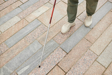 High angle closeup of blind man walking in city and using cane on pavement, copy space