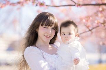 Obraz premium 赤ちゃんとお母さん、桜の木の下で