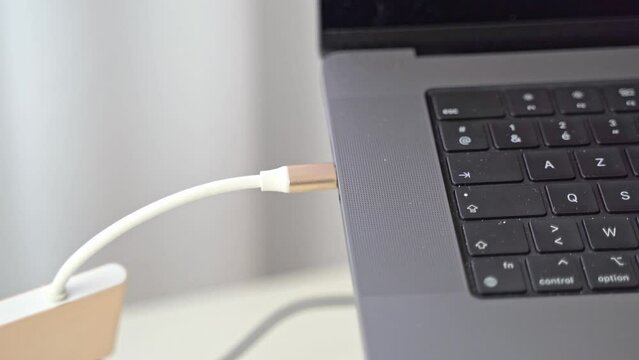 A hand comes into the close-up scene and plugs in a USB-C adaptor for other peripherals