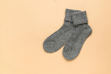 Two warm gray knitted socks on a light beige background. Minimal footwear concept.