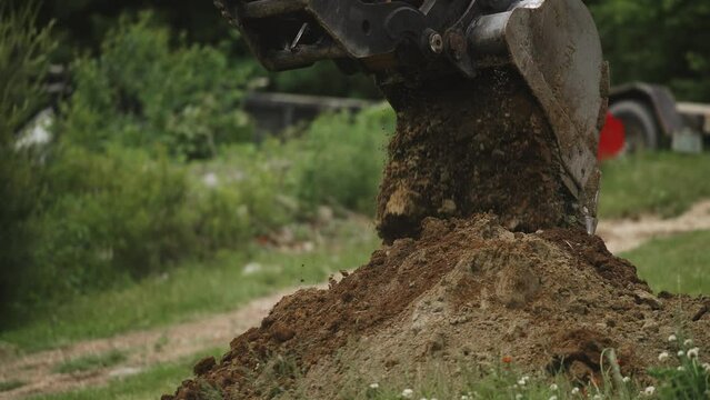 Excavator bucket dumping fresh load of soil dirt detail shot (4k 30p Slow Motion)