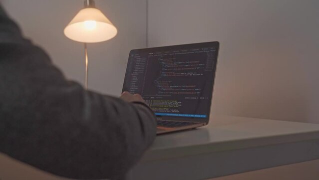 Young male hands appear and move toward an open laptop computer where software editing code is on display.  Work begins on a new piece of software for a website immediately.