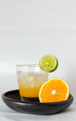 orange drink with ice and lemon on a wooden plate with white background