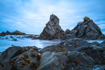 Fototapeta na wymiar Massive volcanic rocks towering on the beach at St. Geroge Point in Crescent City, California. Long exposure photography.