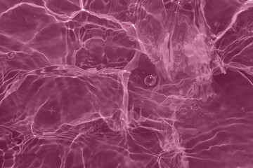 Defocus blurred transparent pink colored clear calm water surface texture with splash, bubble. Shining pink water ripple background. Surface of water in swimming pool. Pink bubble water shining.