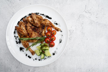 Grilled fried Chicken Tabaka and fresh vegetables on white plate