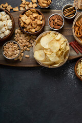 Assortment of salty snacks on dark background.