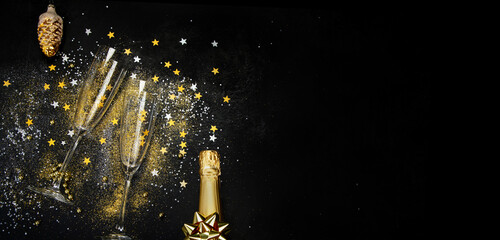 Glass of champagne and bottle on dark background.