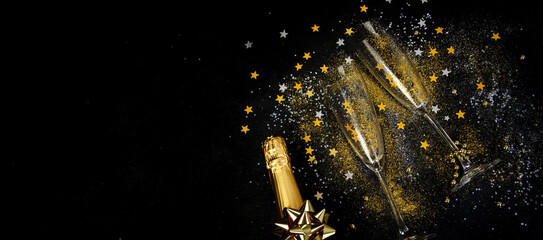 Glass of champagne and bottle on dark background.