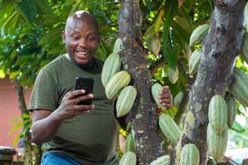 A happy African male farmer, trader, entrepreneur or businessman from Nigeria, holding and looking...