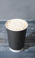 coffee to go in a paper cup. coffee with milk froth, latte or cappuccino on wooden table. takeaway drinks in plastic free cup.