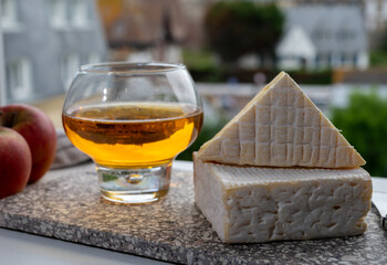 Pairing of apple cider drink with cow cheese pont l'eveque and houses of Etretat village on background, Normandy, France