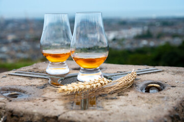 Tasting of single malt scotch whisky in glasses with view from Calton hill to new and old parts of Edinburgh city in rainy day, Scotland, UK
