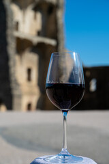 Glass of red dry wine and ruins of medieval castle of Châteauneuf-du-Pape ancient wine making village in France