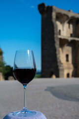 Glass of red dry wine and ruins of medieval castle of Châteauneuf-du-Pape ancient wine making village in France