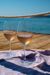 Glasses of cold rose wine from Provence served outdoor on wooden yacht pier with view on blue water and white sandy beach Plage de Pampelonne near Saint-Tropez, France