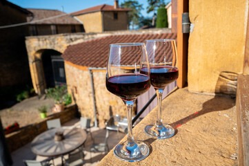 Tasting of red wine by old wine maker in Pierres Dorées region with yellow stone houses on south of Beaujolais region, France