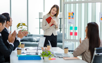 Millennial Asian professional successful young cheerful female  businesswoman speaker lecturer in formal suit standing smiling pointing graph chart information document on glass board in meeting room
