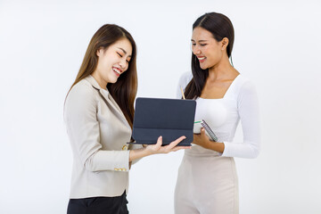 Isolated cutout studio shot Millennial Asian professional successful businesswoman model in formal suit showing tablet computer screen to female colleague writing note on notebook on white background