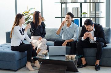 Group of millennial Asian young happy male female businessman businesswoman employee staff in formal business suit sitting on  sofa smiling discussing brainstorming talking together in office.