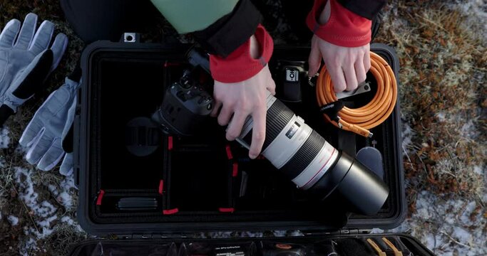 Adventure photographer preparing camera gear from flight case using tools, above