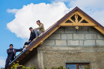 three Roofer man roof carpenter working Country house renovation. looking at camera blue sky...