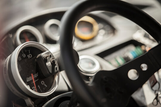 Rally car dashboard gauges and steering wheel close up macro, switches