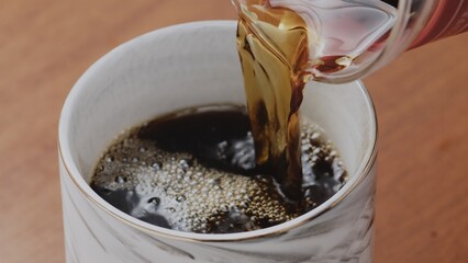 Black specialty coffee being served in mug on wooden table