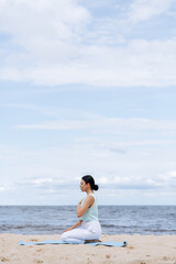 Beautiful european woman doing breathing yoga exercise in the park, European female meditation pose, healthcare.