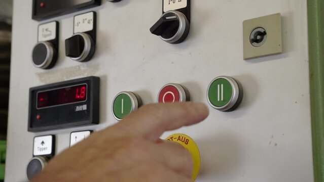 Hand pressing buttons on grinding machine control panel. Choosing power level on industrial machinery