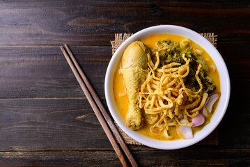 Northern Thai food (Khao Soi), Spicy curry noodles soup with chicken on wooden background, Local Thai food