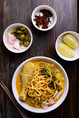 Northern Thai food (Khao Soi), Spicy curry noodles soup with chicken on wooden background, Local Thai food