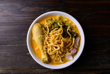 Northern Thai food (Khao Soi), Spicy curry noodles soup with chicken on wooden background, Local Thai food