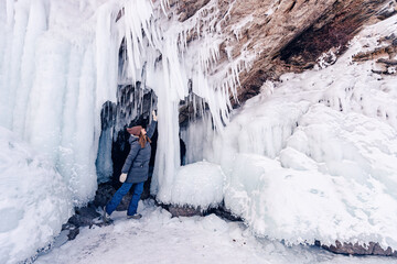 Tourist woman background of frozen grotto and pure ice winter lake Baikal