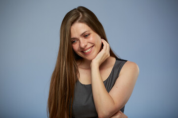 Smiling woman with long hair touching face looking down, isolated portrait on blue background